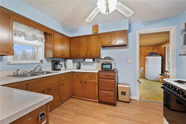 kitchen with sink, range with gas cooktop, white refrigerator, ceiling fan, and light hardwood / wood-style floors