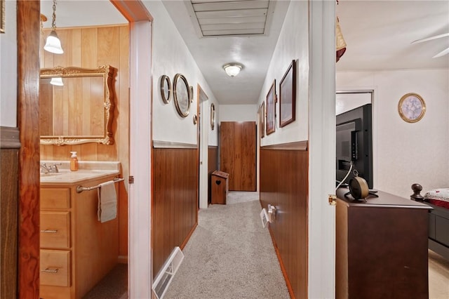 hall featuring light colored carpet and wooden walls