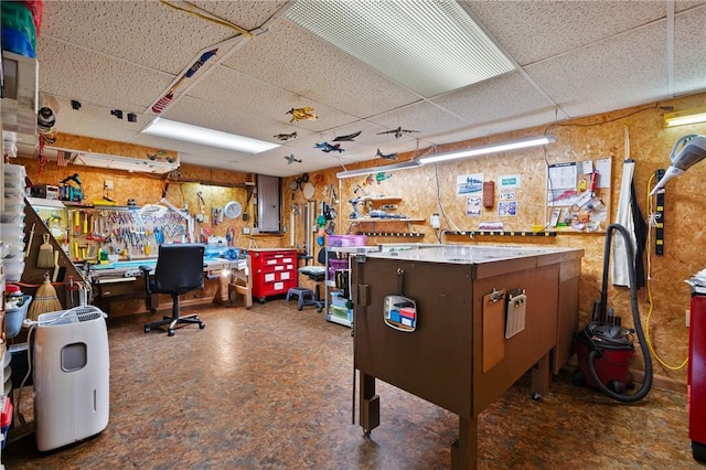 game room with a paneled ceiling, electric panel, and a workshop area