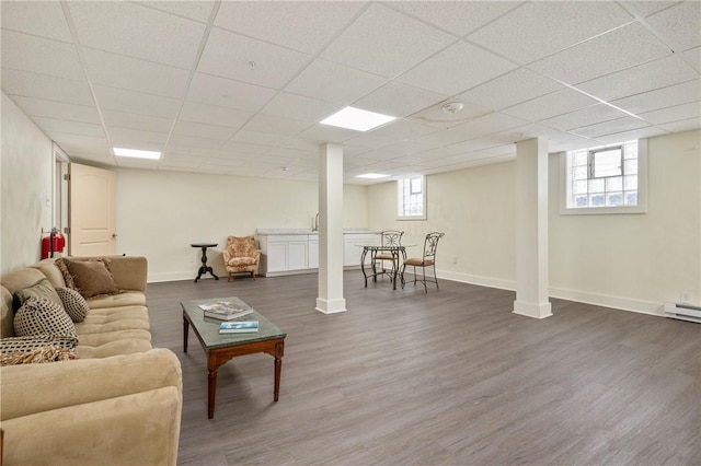 living room with a healthy amount of sunlight, dark hardwood / wood-style floors, and a drop ceiling