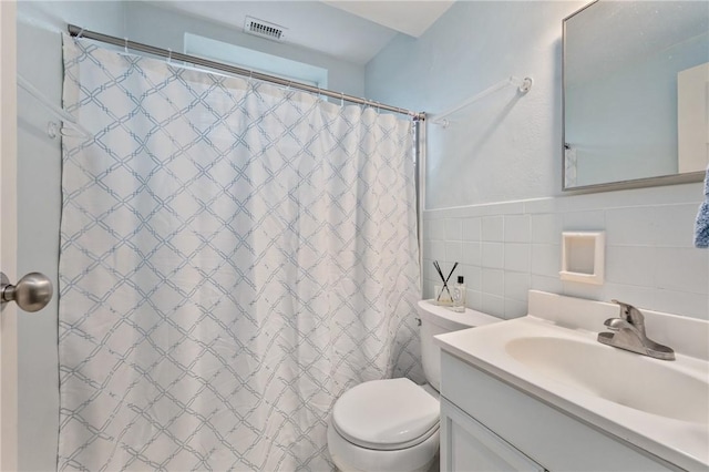 bathroom with vanity, curtained shower, tile walls, and toilet