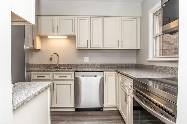 kitchen with sink, electric range oven, dishwasher, light stone countertops, and cream cabinets