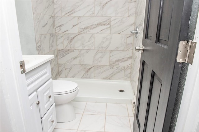 bathroom featuring vanity, tiled shower, and toilet