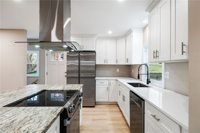 kitchen featuring sink, appliances with stainless steel finishes, white cabinetry, light stone counters, and island range hood