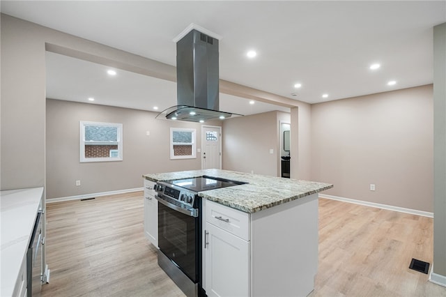 kitchen with white cabinets, stainless steel range with electric stovetop, island exhaust hood, light hardwood / wood-style floors, and light stone countertops