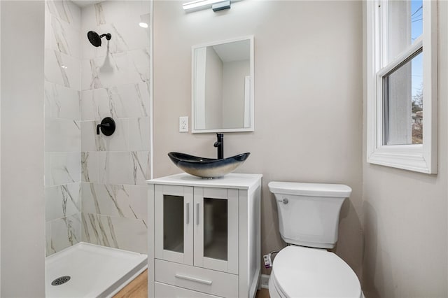 bathroom with tiled shower, vanity, and toilet