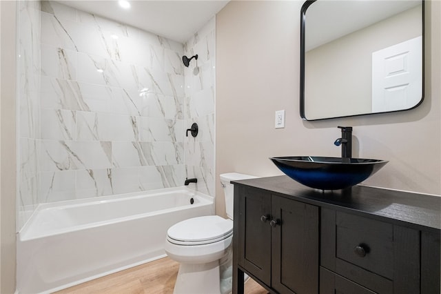 full bathroom with tiled shower / bath combo, vanity, wood-type flooring, and toilet