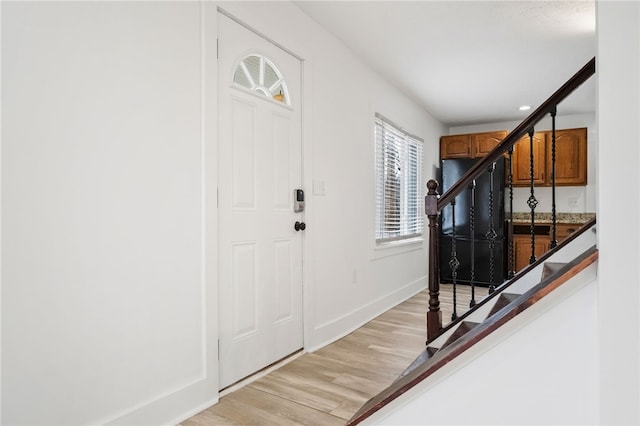 entryway featuring stairway, light wood-type flooring, and baseboards