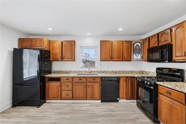 kitchen featuring brown cabinets, a sink, and black appliances