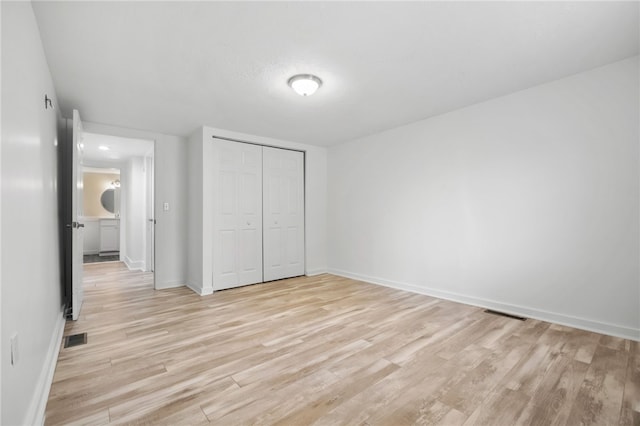 unfurnished bedroom with a closet, light wood-type flooring, visible vents, and baseboards