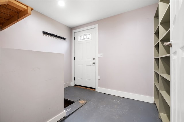 doorway featuring finished concrete floors and baseboards