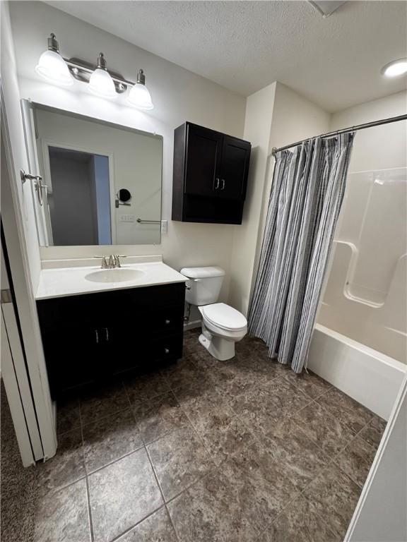 full bathroom featuring vanity, shower / tub combo, a textured ceiling, and toilet