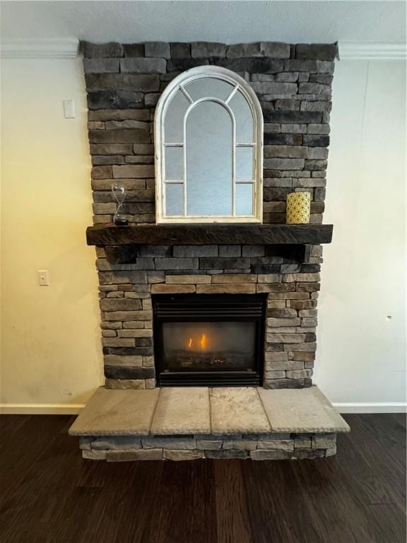 interior details with ornamental molding, a stone fireplace, and hardwood / wood-style floors