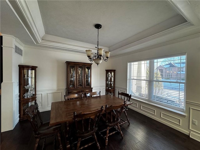 dining space featuring a raised ceiling, crown molding, dark hardwood / wood-style floors, and an inviting chandelier