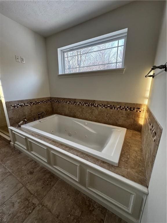 bathroom with tiled tub and a textured ceiling