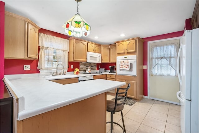 kitchen with a kitchen bar, hanging light fixtures, light tile patterned floors, kitchen peninsula, and white appliances