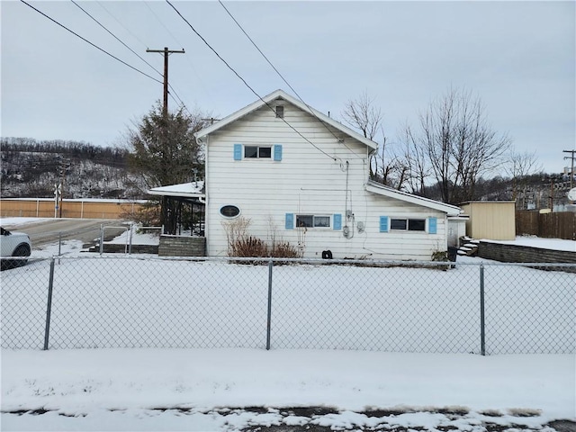 snow covered rear of property featuring a storage unit