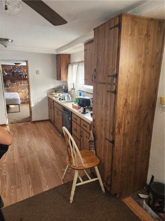 kitchen with black dishwasher, sink, and light wood-type flooring