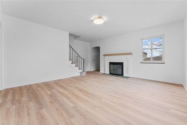 unfurnished living room with a brick fireplace and light hardwood / wood-style flooring