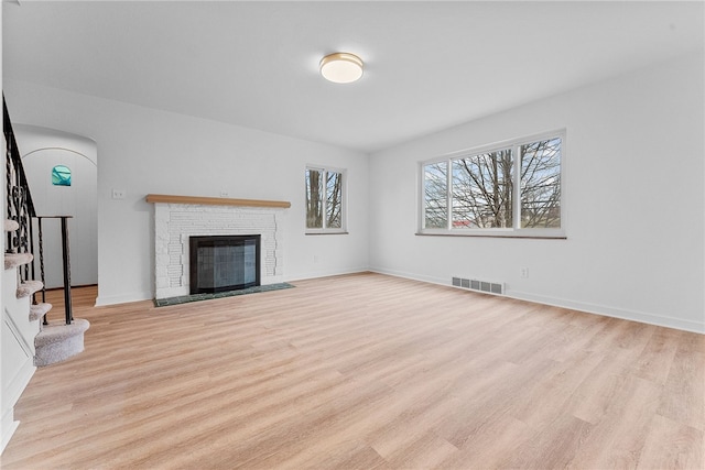 unfurnished living room featuring a brick fireplace and light wood-type flooring