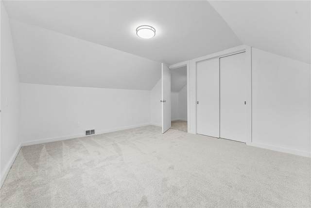 bonus room with lofted ceiling and light carpet