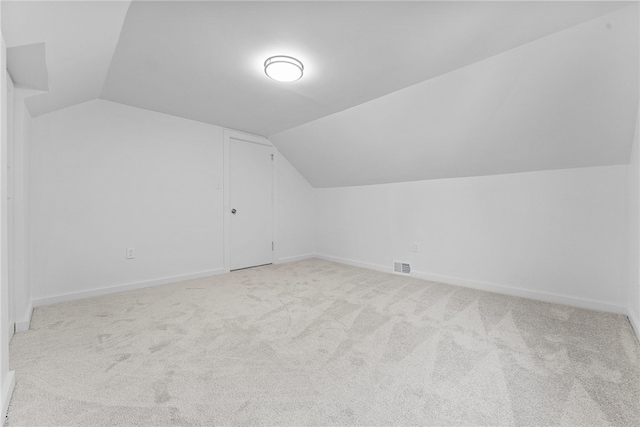 additional living space featuring light carpet and vaulted ceiling