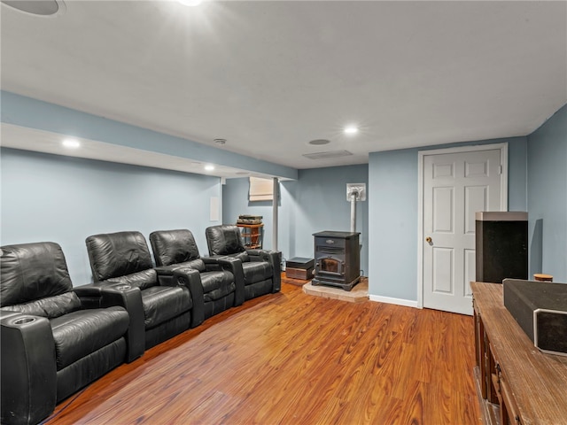 home theater room with hardwood / wood-style flooring and a wood stove