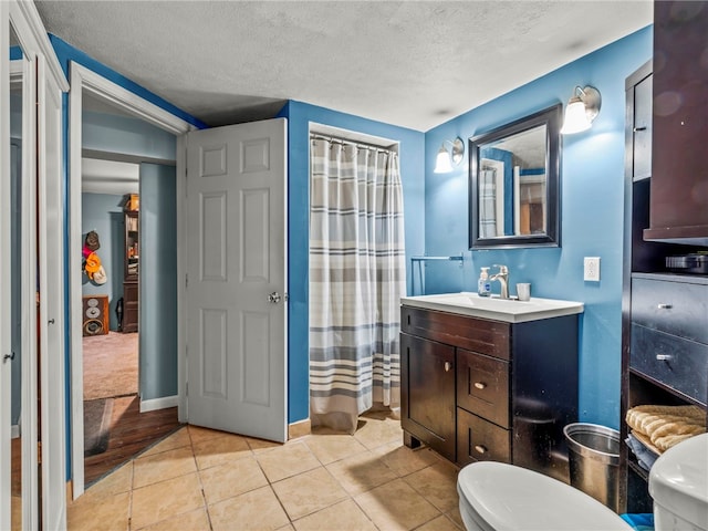 bathroom with tile patterned flooring, vanity, a textured ceiling, toilet, and walk in shower