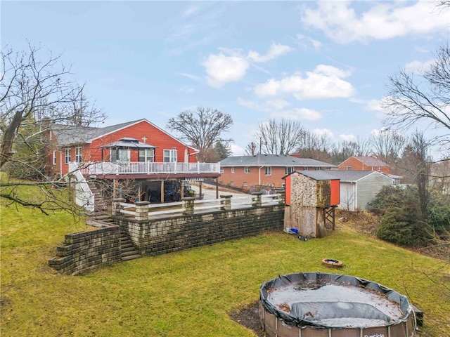 back of house with a fire pit, a lawn, and a deck