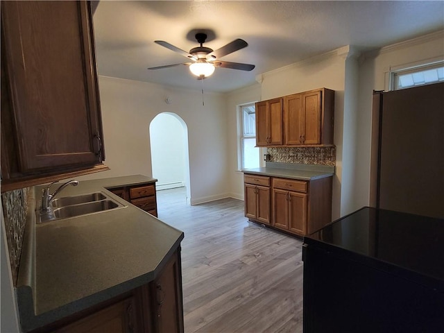 kitchen featuring sink, decorative backsplash, ornamental molding, ceiling fan, and light wood-type flooring