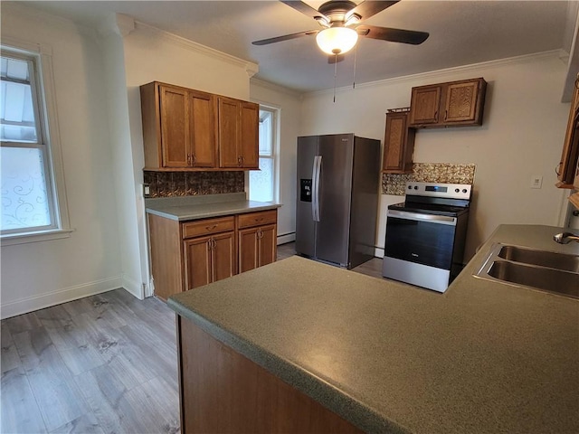 kitchen featuring sink, ornamental molding, appliances with stainless steel finishes, light hardwood / wood-style floors, and decorative backsplash