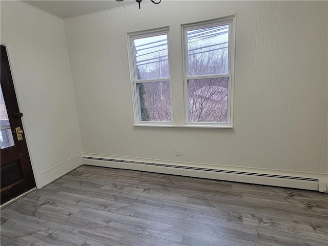 empty room with a baseboard heating unit and light hardwood / wood-style floors