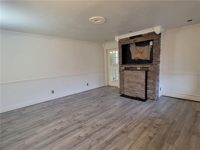 unfurnished living room featuring a fireplace, ornamental molding, baseboard heating, and light wood-type flooring
