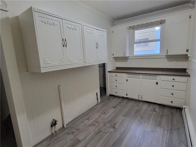 kitchen with a baseboard heating unit, ornamental molding, white cabinets, and light wood-type flooring