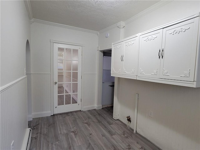 washroom with ornamental molding, a baseboard heating unit, a textured ceiling, and light wood-type flooring
