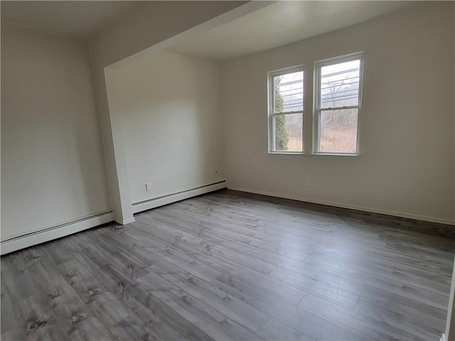 spare room featuring a baseboard heating unit and light wood-type flooring