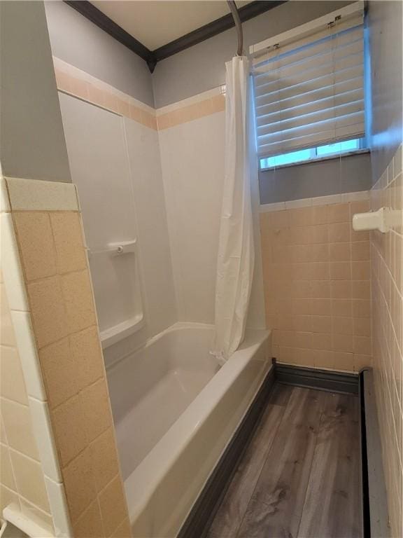 bathroom featuring shower / bathtub combination with curtain, hardwood / wood-style flooring, ornamental molding, and tile walls