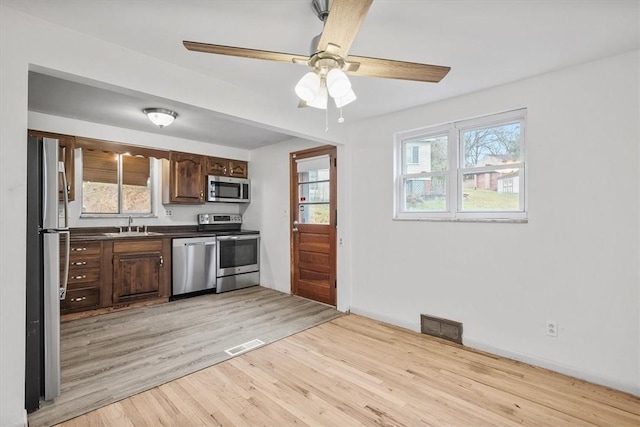 kitchen with sink, light hardwood / wood-style flooring, ceiling fan, appliances with stainless steel finishes, and dark brown cabinetry