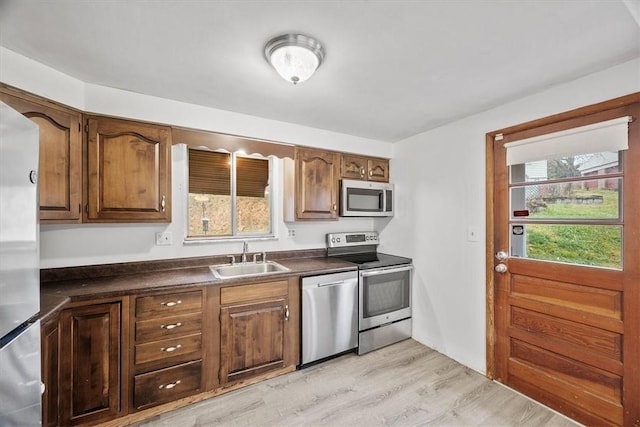 kitchen featuring a healthy amount of sunlight, appliances with stainless steel finishes, sink, and light hardwood / wood-style flooring