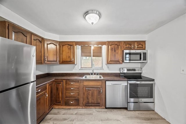 kitchen featuring stainless steel appliances, sink, and light wood-type flooring