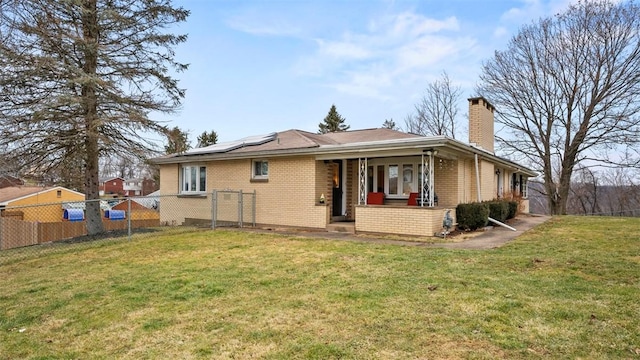 rear view of house with a yard and solar panels