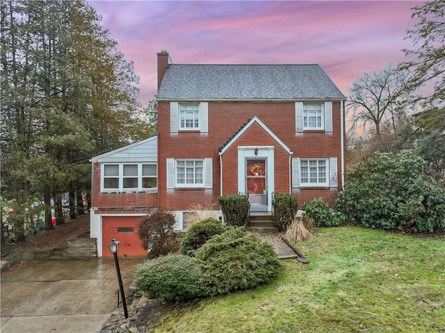 colonial-style house with a garage and a lawn