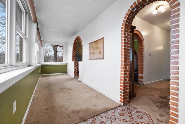 corridor featuring light carpet and a textured ceiling