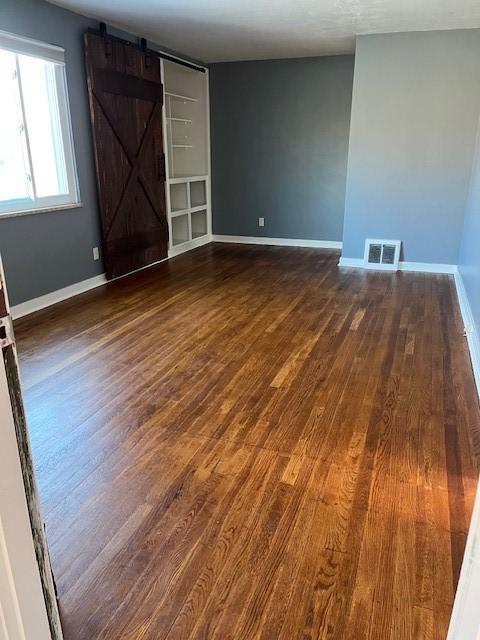 spare room with a barn door and dark hardwood / wood-style flooring