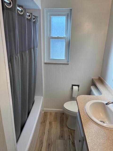 full bathroom featuring vanity, hardwood / wood-style floors, shower / bath combination with curtain, and toilet