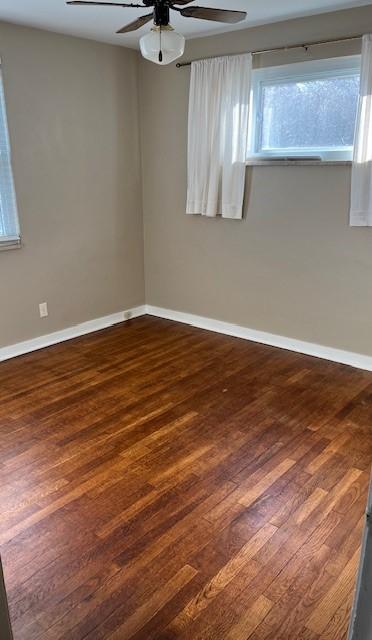 empty room with dark wood-type flooring and ceiling fan