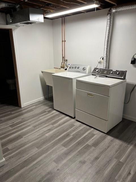 laundry room featuring washing machine and clothes dryer, sink, and hardwood / wood-style floors