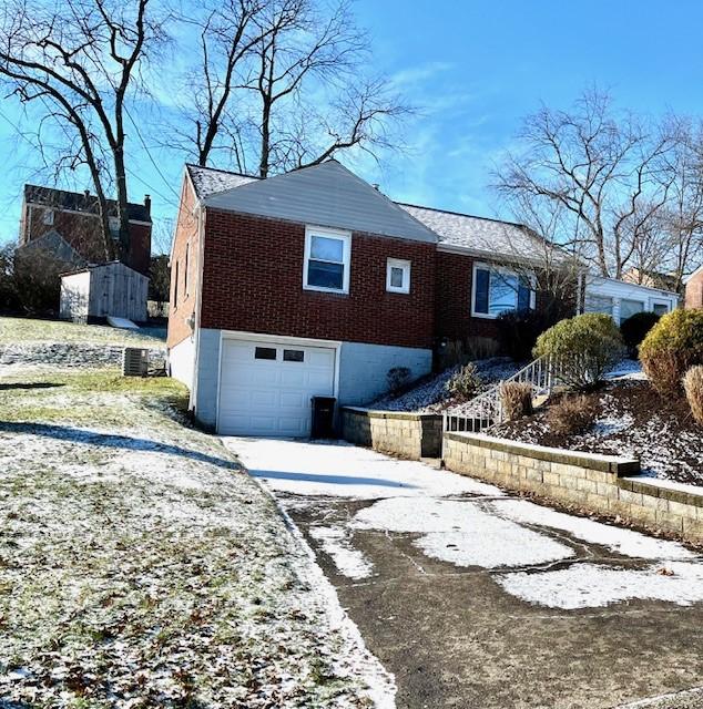 view of snow covered exterior with a garage and central air condition unit