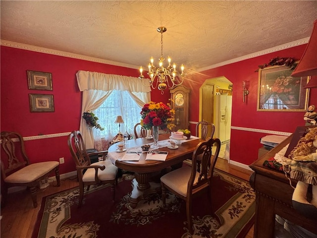 dining space with crown molding, hardwood / wood-style floors, a textured ceiling, and a chandelier