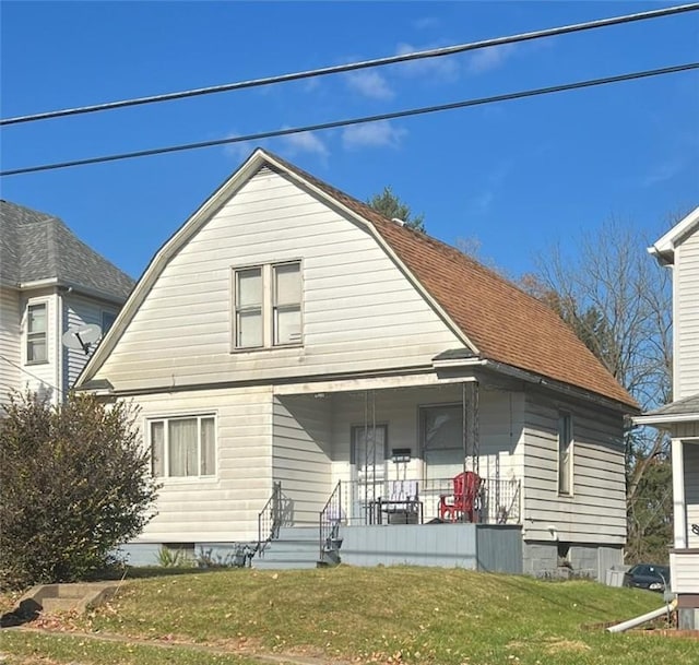 rear view of house with covered porch and a lawn